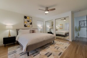 Relax in this serene bedroom with a large bed, nightstands, and a ceiling fan above.