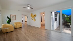 A spacious living room with hardwood flooring, a ceiling fan, and a large sliding glass door leading to an outdoor area.