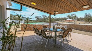 Een terras buiten met een tafel en stoelen, een stenen muur en uitzicht op het landschap.