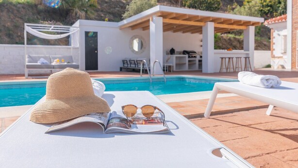A poolside area with lounge chairs, a hat, sunglasses, and a magazine. - Villa Tres Flores Cómpeta by Ruralidays (Málaga)