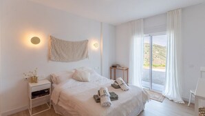 A bedroom with a bed, bedside table, and a view of the outdoors. - Villa Tres Flores Cómpeta by Ruralidays (Málaga)