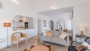 A modern living room with a grey sofa, wicker chairs, a round coffee table, and a small side table with a lamp. - Villa Tres Flores Cómpeta by Ruralidays (Málaga)