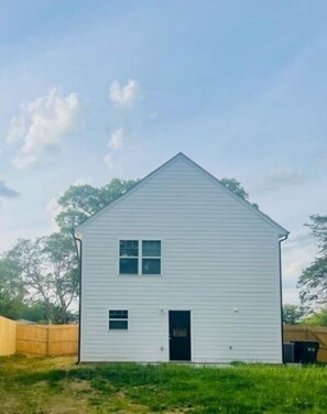 Standalone cottage with a symmetrical facade, featuring a black door and two windows.