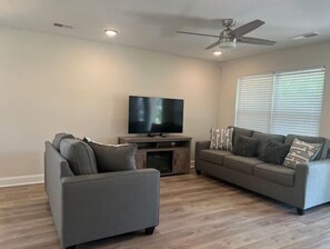 Relax in this stylish living room with a large flat-screen TV, two comfortable sofas, and a ceiling fan.
