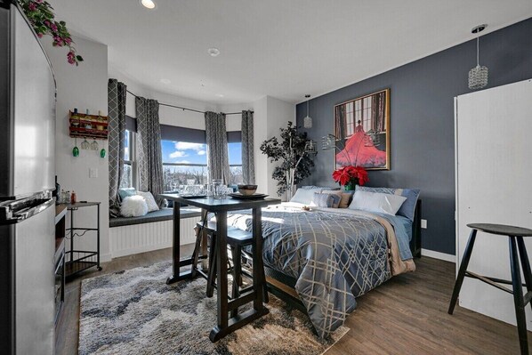 A modern bedroom with a bed, a dining table, and a window with curtains. - Beacon Hotel (Beacon)
