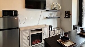 Eine moderne Küche mit integriertem Mikrowellenherd, einem Edelstahlkühlschrank, einem Kamin und einem Essbereich mit einem dunklen Holztisch und Stühlen.