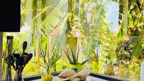Een keuken met een groot raam met uitzicht op een weelderige tuin.