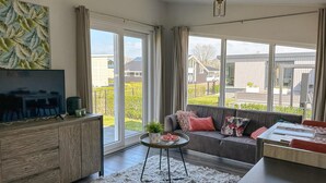 Een moderne woonkamer met een bank, televisie en een bijzettafeltje met een plantje.