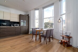A modern kitchen with a dining area, wooden flooring, and large windows. - GuestReady - Spacious 2BR | Near Little Venice (London)
