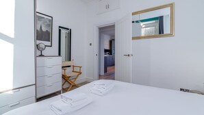 Ein Hotelzimmer mit Bett, Schreibtisch, Stuhl, Kleiderschrank, Spiegel und einer Tür zum Badezimmer.