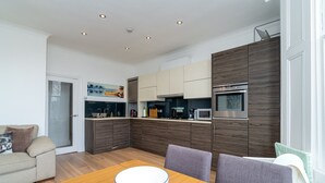Eine moderne Küche mit dunklen Holzschränken, einem eingebauten Backofen und einer Mikrowelle. Ein Esstisch mit einer Schüssel in der Mitte.