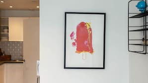 A framed abstract painting on a white wall in a modern kitchen with white cabinets and a grey backsplash. - GuestReady - Amazing spot near Gilbert Park (London)