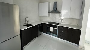 Een moderne keuken met witte metrotegels, donkere kasten, een roestvrijstalen spoelbak en een ingebouwde oven.