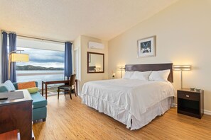 Enjoy a serene view of the water and mountains from this room, featuring a large bed, desk, and chair.