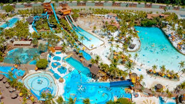 Un resort con varias piscinas, toboganes acuáticos y palmeras.