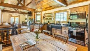 Uma cozinha rústica com vigas de madeira, uma área de jantar com mesa de madeira e um espaço de estar acolhedor com um sofá.
