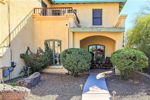 A two-story building with a balcony, a covered patio, and a gravel driveway.