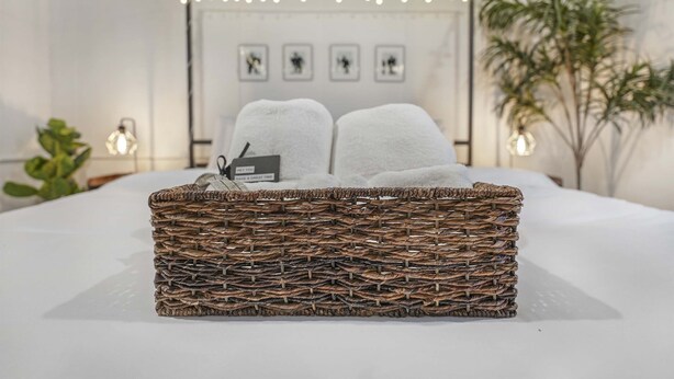 A neatly made bed with a wicker basket containing two towels and a tag. - ~CBS Featured~ HUGE HOT TUB|CINEMA|Firepit (South Bend)