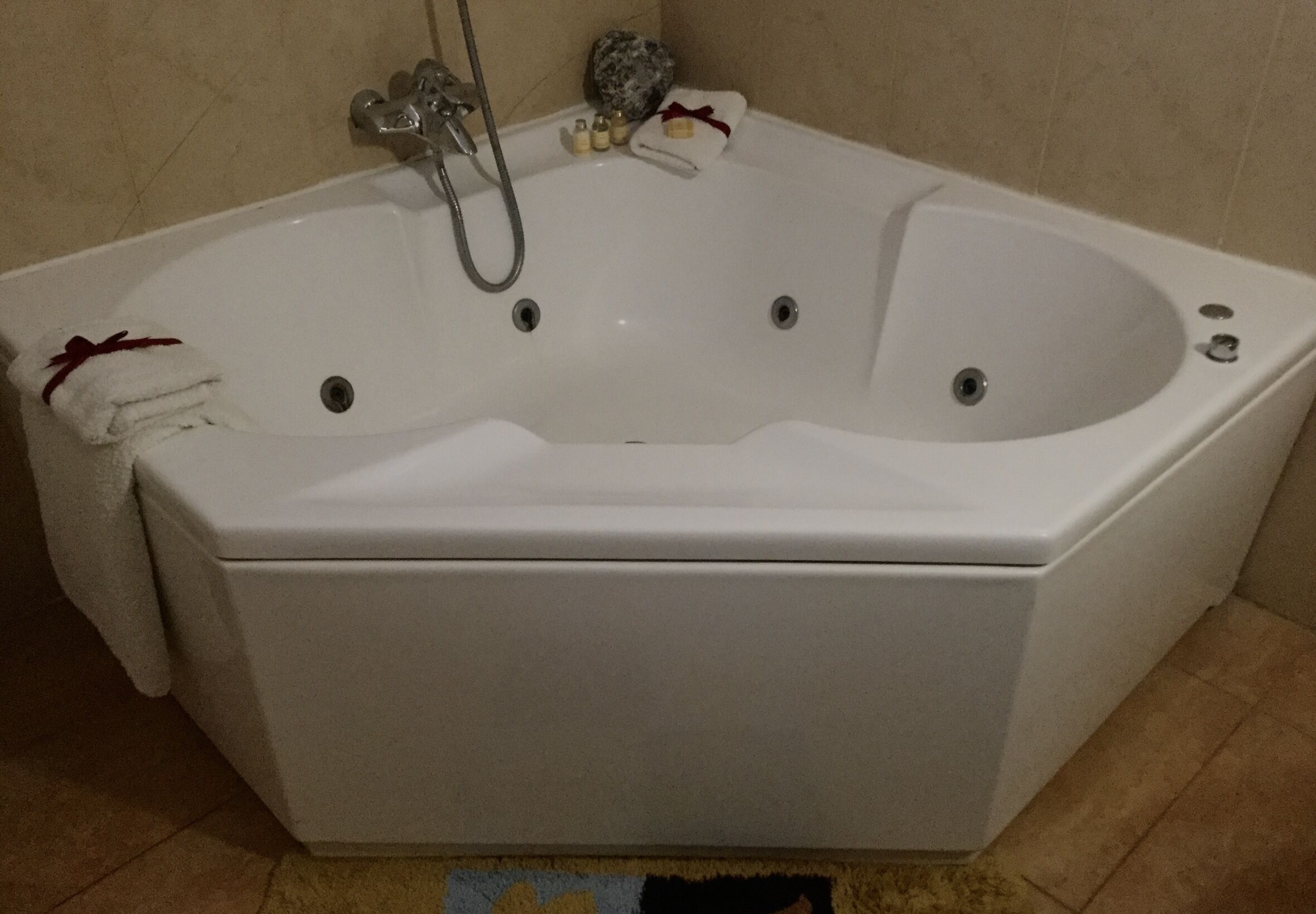 Una bañera blanca con ducha, una toalla y una botella de champú.