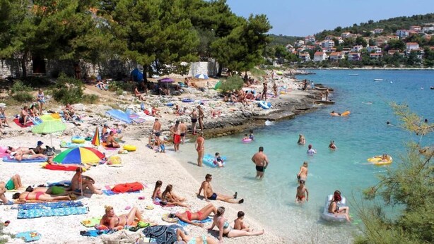 A crowded beach with people sunbathing, swimming, and using inflatable floats. - Villa with pool 50 m from the sea (Okrug Gornji)