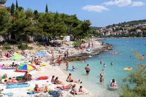 A crowded beach with people sunbathing, swimming, and using inflatable floats. - Villa with pool 50 m from the sea (Okrug Gornji)
