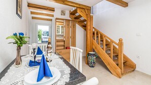A dining area with a table set for two, a vase with flowers, and a wooden staircase. - Stunning home in Jurdani with WiFi (Jurdani)
