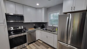Una cocina moderna con electrodomésticos de acero inoxidable, armarios blancos y un salpicadero con motivo de espiga.