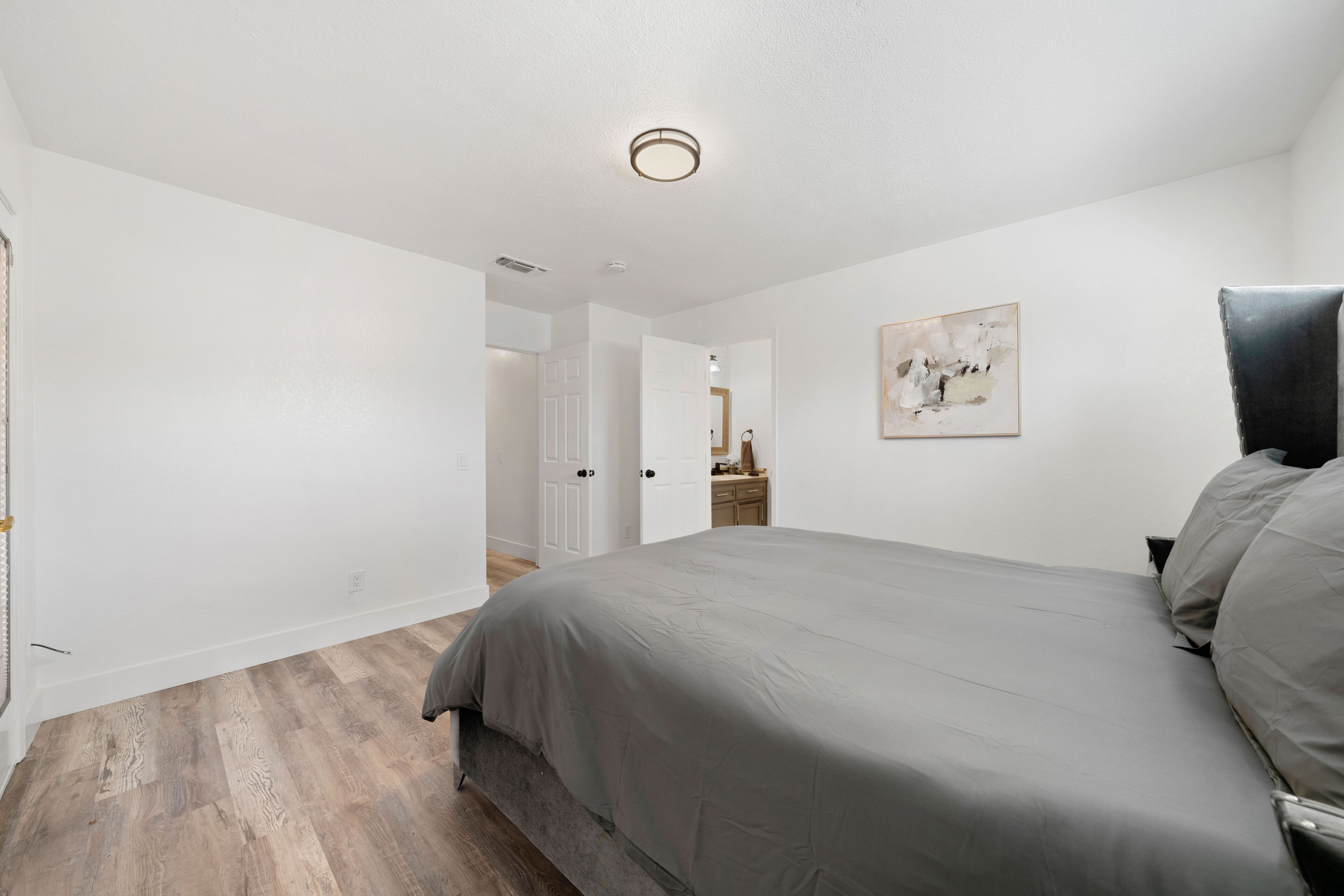 A bedroom with a bed, a dresser, and a painting on the wall.