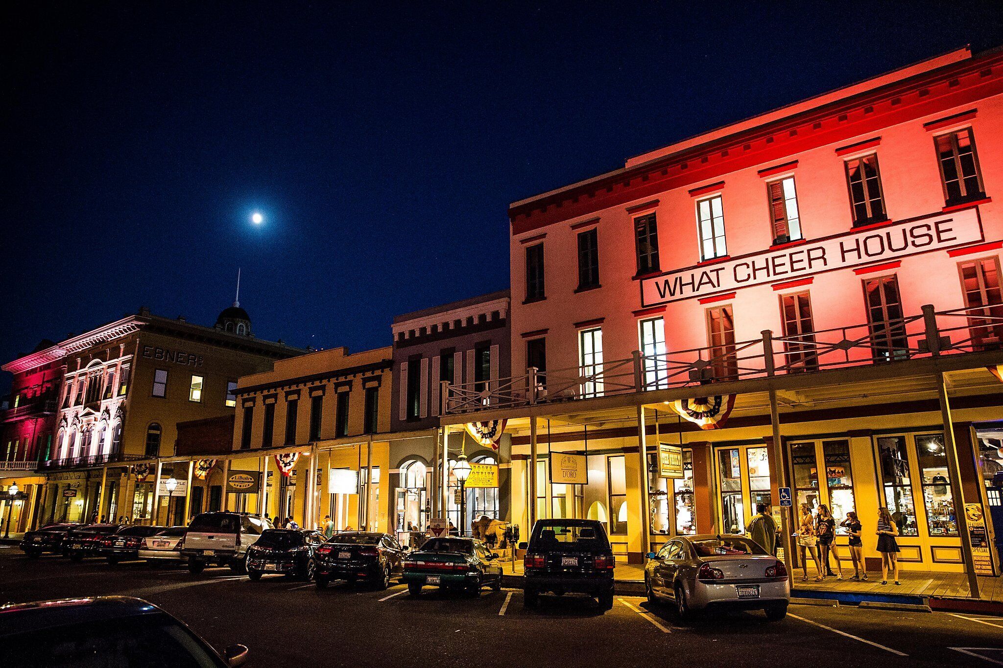 A street scene with a building labeled 'WHAT CHEER HOUSE' at night.