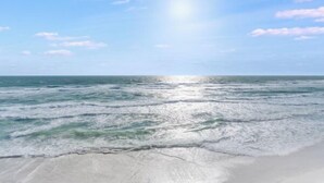 Una playa con cielos despejados y luz solar reflejada en el agua.