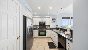 Una cocina moderna con armarios blancos, electrodomésticos de acero inoxidable, microondas, horno y lavavajillas.