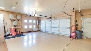 Een ruime garage met een grote witte garagedeur, verlichting en diverse gereedschappen en apparatuur.