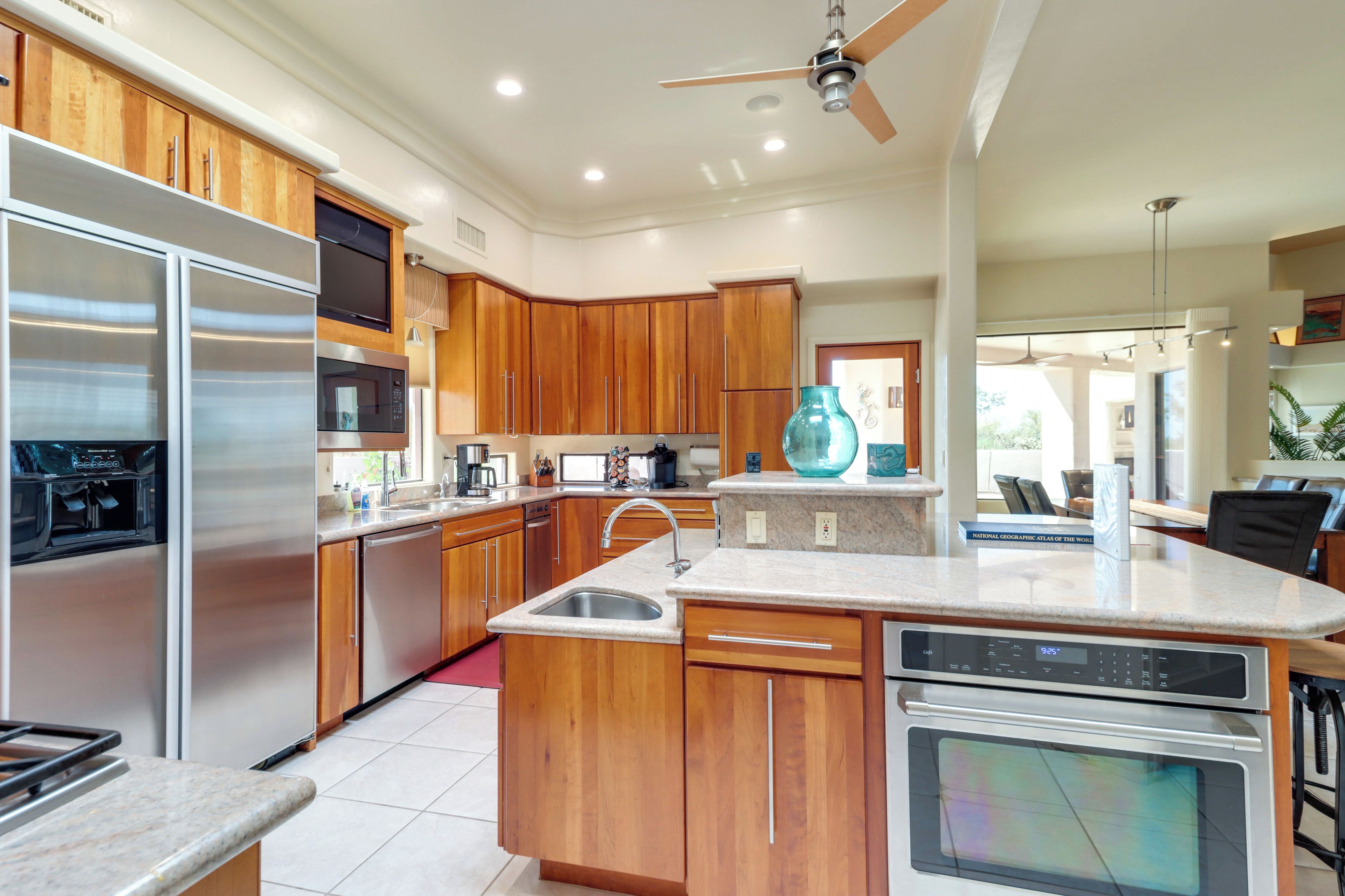 A modern kitchen with wooden cabinets, stainless steel appliances, and a central island with a sink.