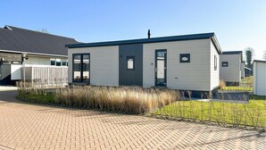 Une maison mobile moderne de plain-pied, avec une façade grise et un toit foncé.