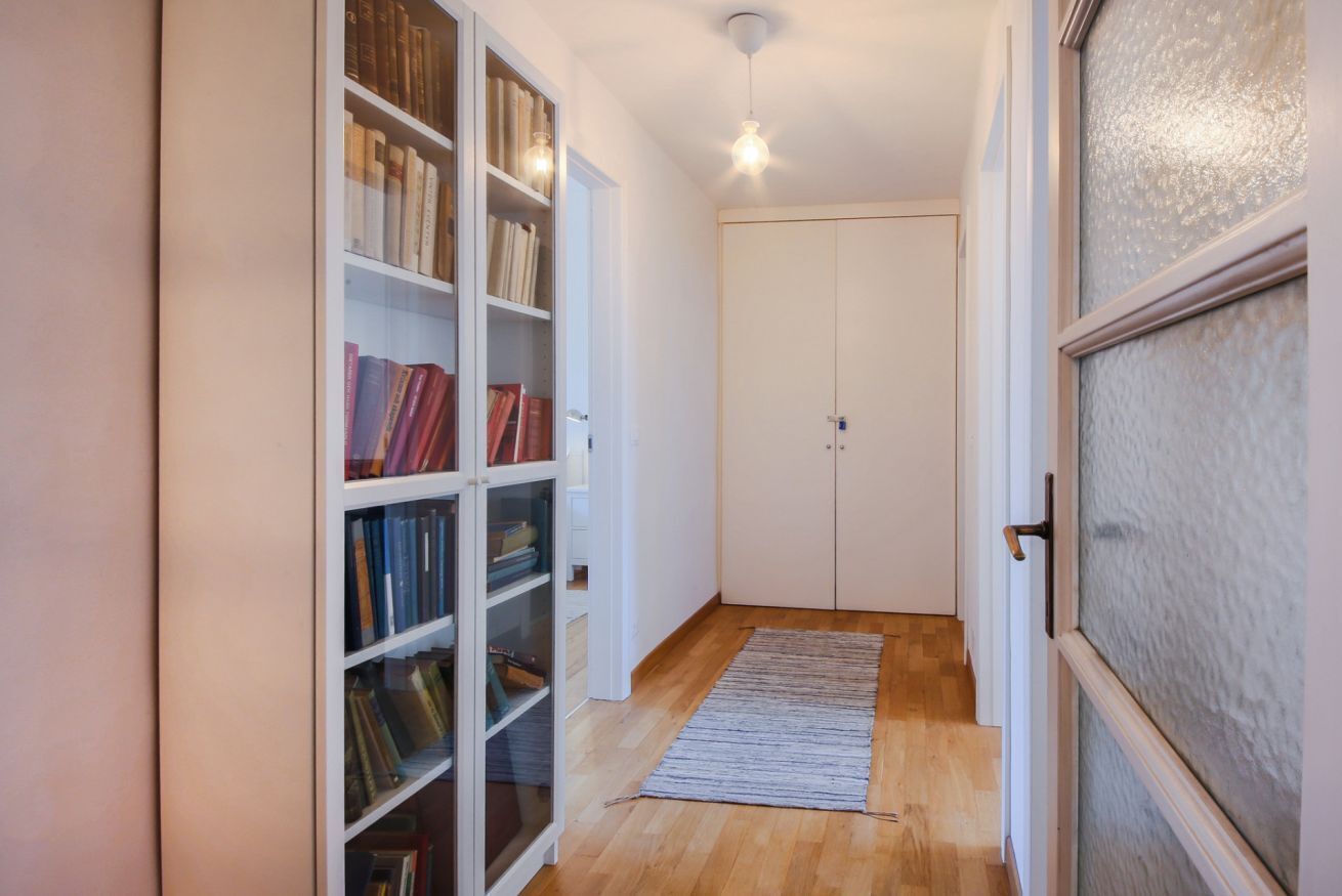A hallway with a bookshelf, a door, and a wooden floor.