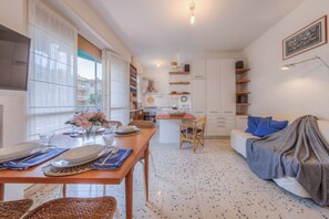 Una cocina moderna con zona de comedor, sofá y televisor.