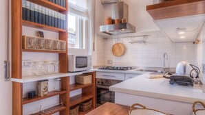 Une cuisine moderne avec des meubles blancs, un four à micro-ondes, une cuisinière et un porte-ustensiles suspendu.