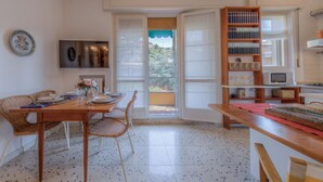 Un coin repas avec une table en bois, des chaises en osier, un téléviseur et une bibliothèque.