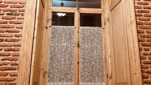 Ein Holzrahmenfenster mit einer Ziegelwand und einer Holztür darunter.