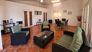 A spacious living area with a sofa, chairs, a coffee table, a dining table, and a ceiling fan. - Villas Rossen  (Puerto Plata)