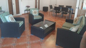 A living room with wicker furniture, a coffee table, and a dining area with chairs and a table. - Villas Rossen  (Puerto Plata)