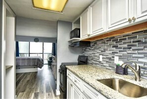 Kitchen features a granite countertop, stainless steel sink, and white cabinetry, with a microwave and toaster on the countertop.