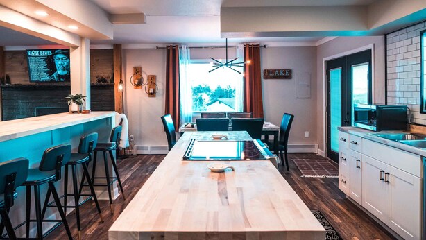A modern kitchen with a central island, bar seating, and a dining area with a large table.