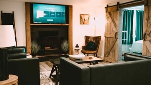 A modern living room with a fireplace, a television, and a large sliding barn door.