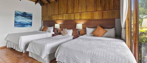 Habitación de hotel con dos camas, vigas de techo de madera, un ventanal grande y un cuadro en la pared.