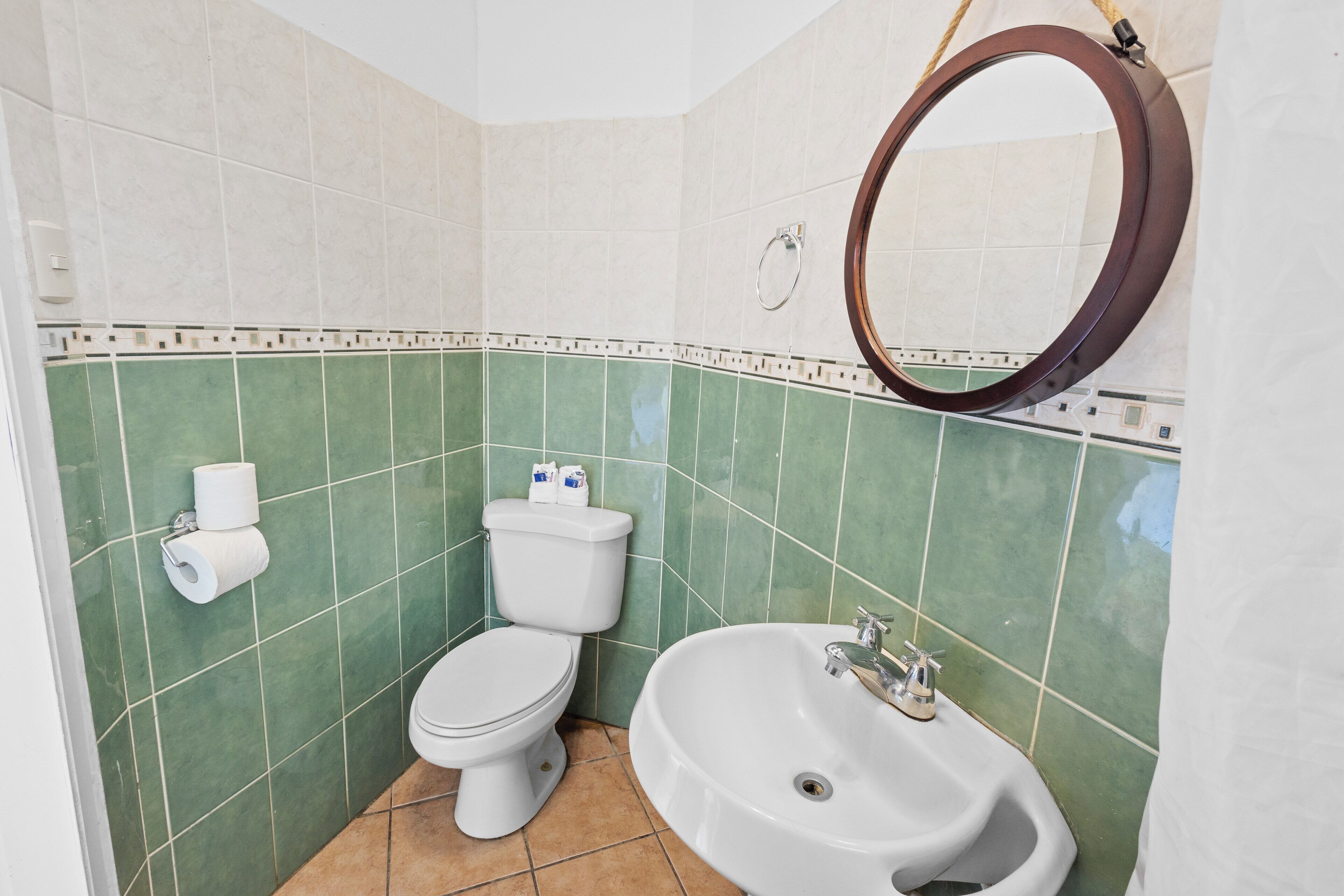 A bathroom with a toilet, sink, and mirror.