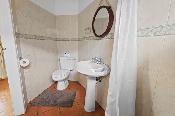 Un baño con inodoro, lavamanos y espejo.
