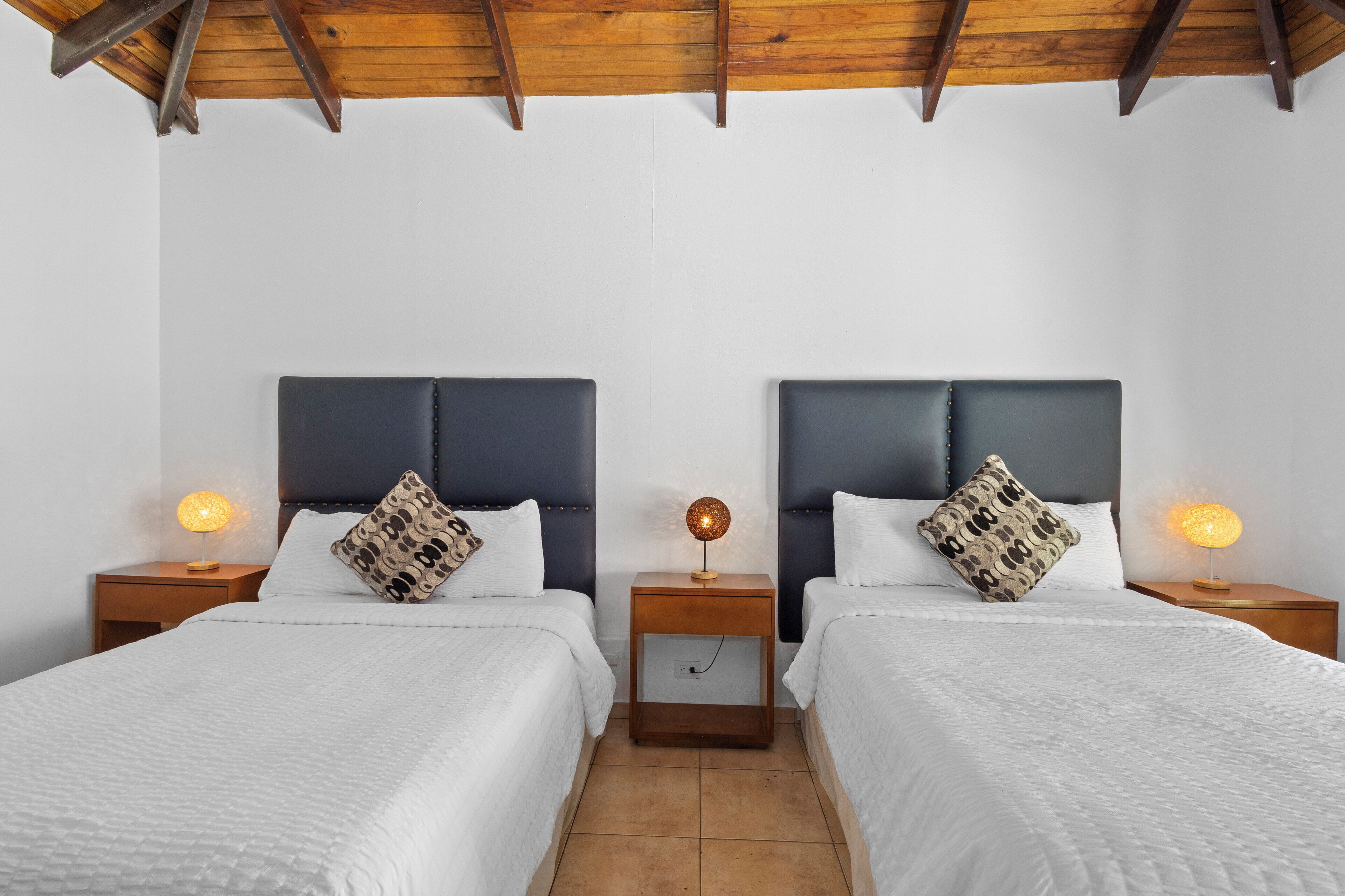 A double room with two beds, each with a headboard and bedside tables with lamps.