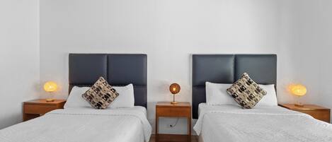 A double room with two beds, each with a headboard and bedside tables with lamps.