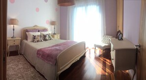 A bedroom with a bed, bedside tables, a chair, and a wardrobe. - The Best Sea View in Madeira -Casa Farol  (Fajã da Ovelha)